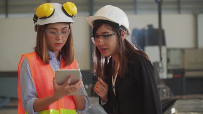 两名使用平板电脑的亚洲女性建筑工程师在建筑工地车间检查工作。