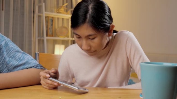 快乐的亚洲儿童兄弟姐妹在夜间在家中一起通过智能手机玩网络游戏，生活方式概念。