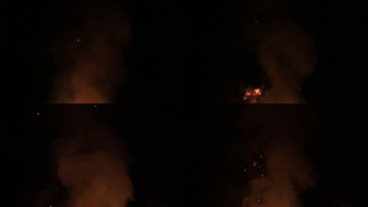 傍晚时分，火焰和烟雾减慢了黑暗背景上的火势和烟雾。