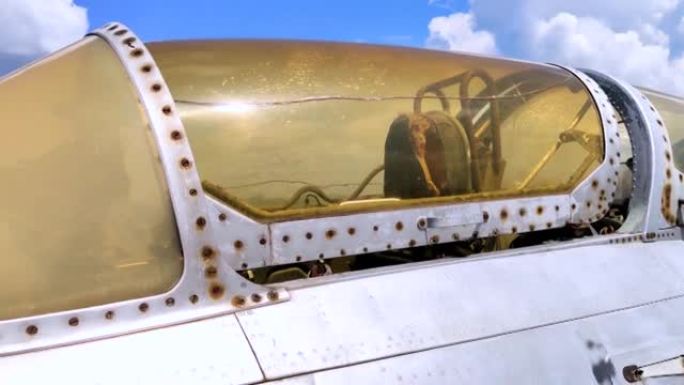 军事战斗机飞行员驾驶舱的特写镜头。玻璃上可见裂纹，随着年龄的增长，裂纹已变成黄色。退役的军事装备。飞