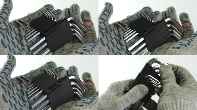 戴着建筑脏手套的人拿着全套六角钥匙。