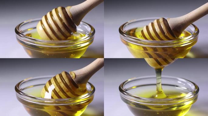 新鲜的金色蜂蜜从木制蜜勺中倒出精美