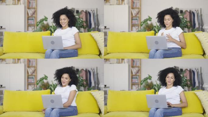 一位年轻的非洲裔美国妇女在便携式笔记本电脑上进行视频通话时的肖像。黑发，卷发，坐在明亮的家庭房间里的