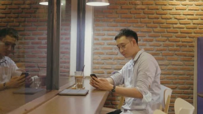 中年商人在炒股视频中喝完咖啡后在咖啡馆的在线聊天中查看消息