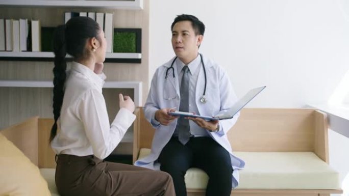 亚洲男医生在诊所就诊时与女性患者交谈。
