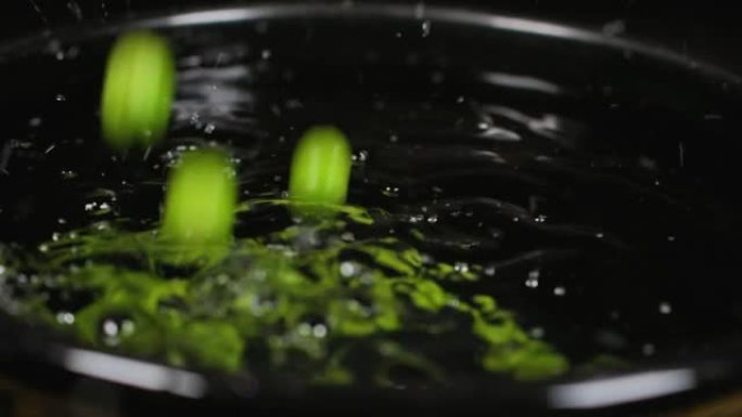 慢动作关闭下降的绿豌豆背景。宏观拍摄新鲜有机豌豆掉落。蔬菜收获健康饮食。美丽的纹理特写新鲜的绿豌豆。