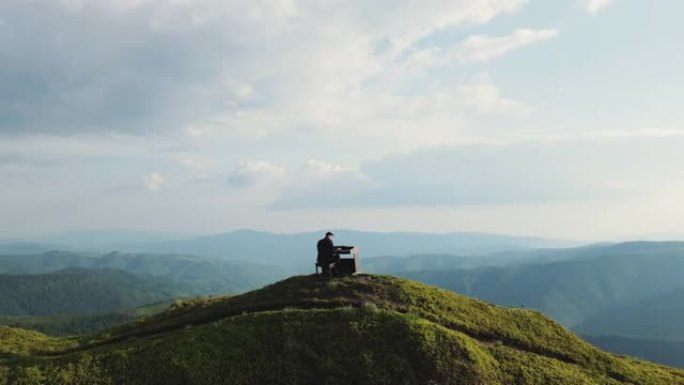 人的鸟瞰图两只手在大自然的三角钢琴上演奏柔和的古典音乐。钢琴家在山上用三角钢琴演奏。专业钢琴家。男子