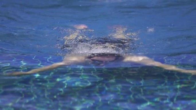 SLO MO-Man在游泳池里游泳蛙泳，看着相机