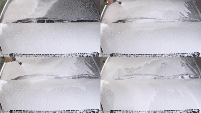用于消失和清洁的白色泡沫在车辆的前车裙体周围流动。化学雪泡沫洗车概念清洁产品。