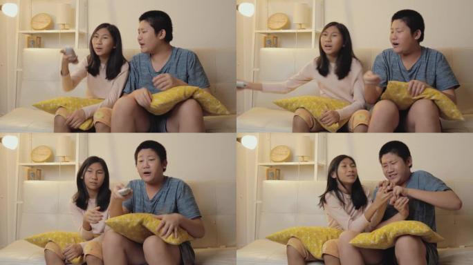 亚洲儿童争取遥控器，晚上在家一起看电视，生活方式理念。