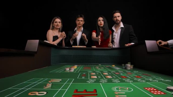 一群男人和女人站在一张绿色的双骰桌旁。穿红衣服的女士掷骰子输了。公司非常不安。从游戏表内查看。慢动作