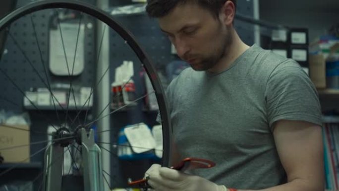 专业自行车机械师及时调整一个辐条张紧辐条的专用工具。山地自行车修理。主固定轮辐条在自行车维修店工作。