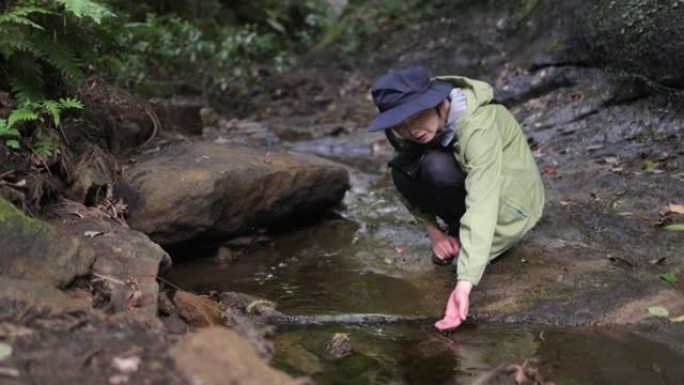 女人在自然界的小溪上抚摸水