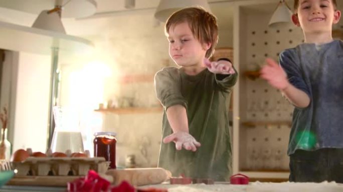 两个小男孩在厨房里玩面粉。