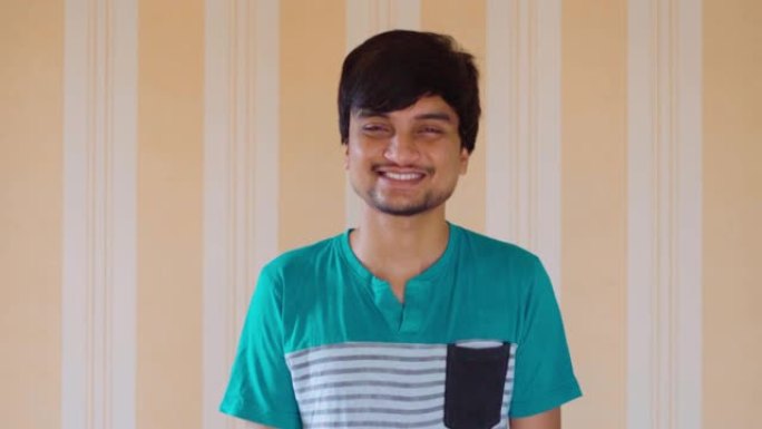 正面25岁的印度男性微笑着看着相机的头部照片。成功的青少年凝视着相机，快乐的学生或实习新员工的肖像