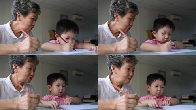 亚洲中国微笑的成熟女人在办公室用数字平板电脑在线美术课上陪孙子