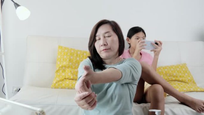 亚洲母亲在新型冠状病毒肺炎期间在家工作时锻炼女儿，检疫生活方式概念。