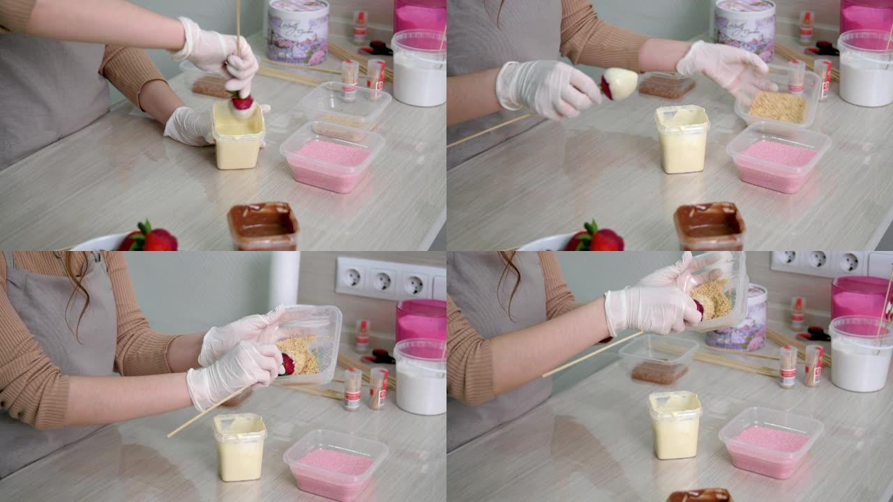 戴白手套的女孩在白巧克力和磨碎的核桃中准备草莓。