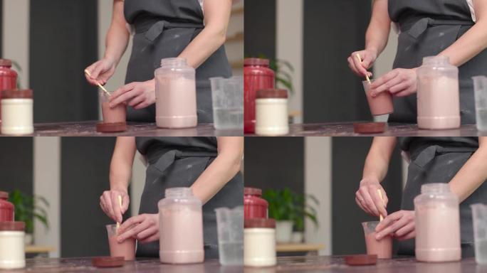 釉料的制备。女人的手在罐子里搅拌釉。