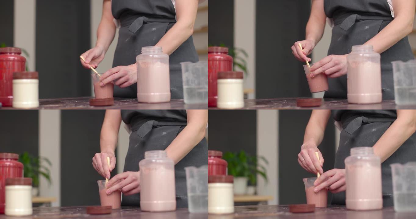 釉料的制备。女人的手在罐子里搅拌釉。