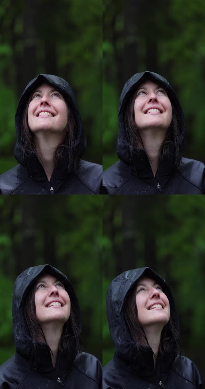 幸福女人在雨中森林徒步旅行并穿着雨衣