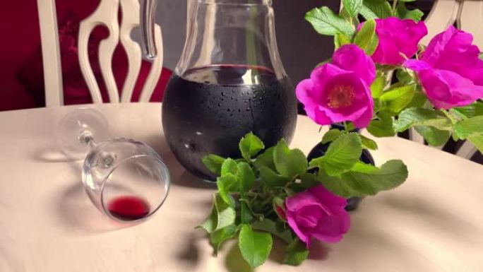 自制红酒在玻璃水罐，鲜花和酒杯在房间的白色桌子上