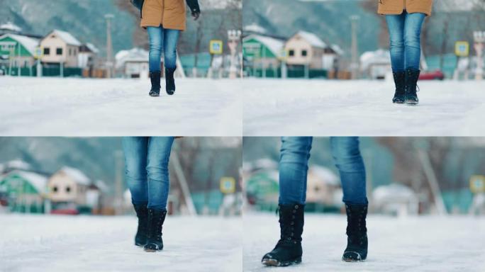 一名妇女小心翼翼地沿着积雪覆盖的小路行走，以免滑倒。底视图。腿的特写