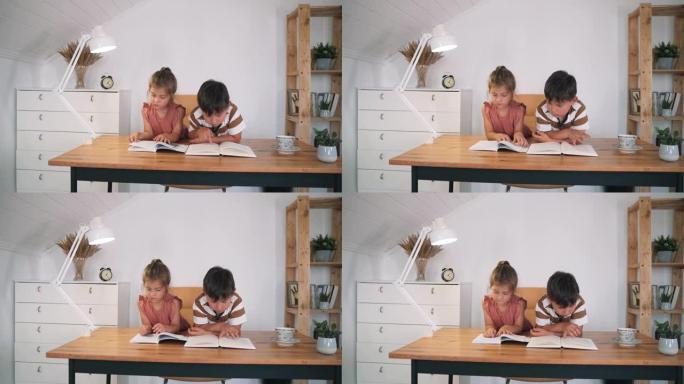 一个男孩和一个女孩坐在桌子上看书。孩子们正在做作业。家庭教育。自我隔离。儿童课程。慢动作