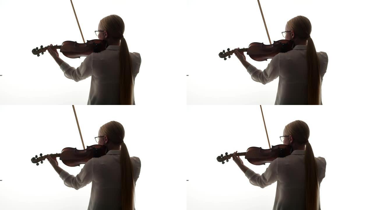穿着白色上衣的女小提琴手拉小提琴，背站在工作室的白色背景上。音乐教育理念与爱好
