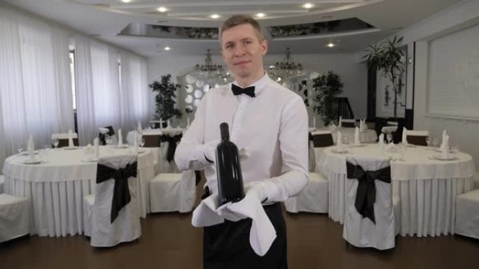 服务员在餐厅拿着一瓶酒的肖像。