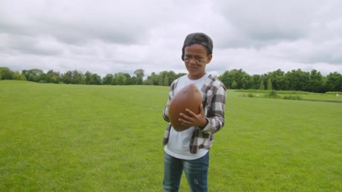 微笑可爱的黑人男生，球场上有美式橄榄球球