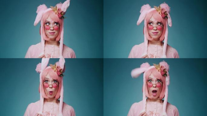 粉红色可爱的糖果动漫女孩与兔子耳朵和粉红色太阳镜的特写镜头使情感的鬼脸和挥舞她的耳朵孤立在蓝色背景。