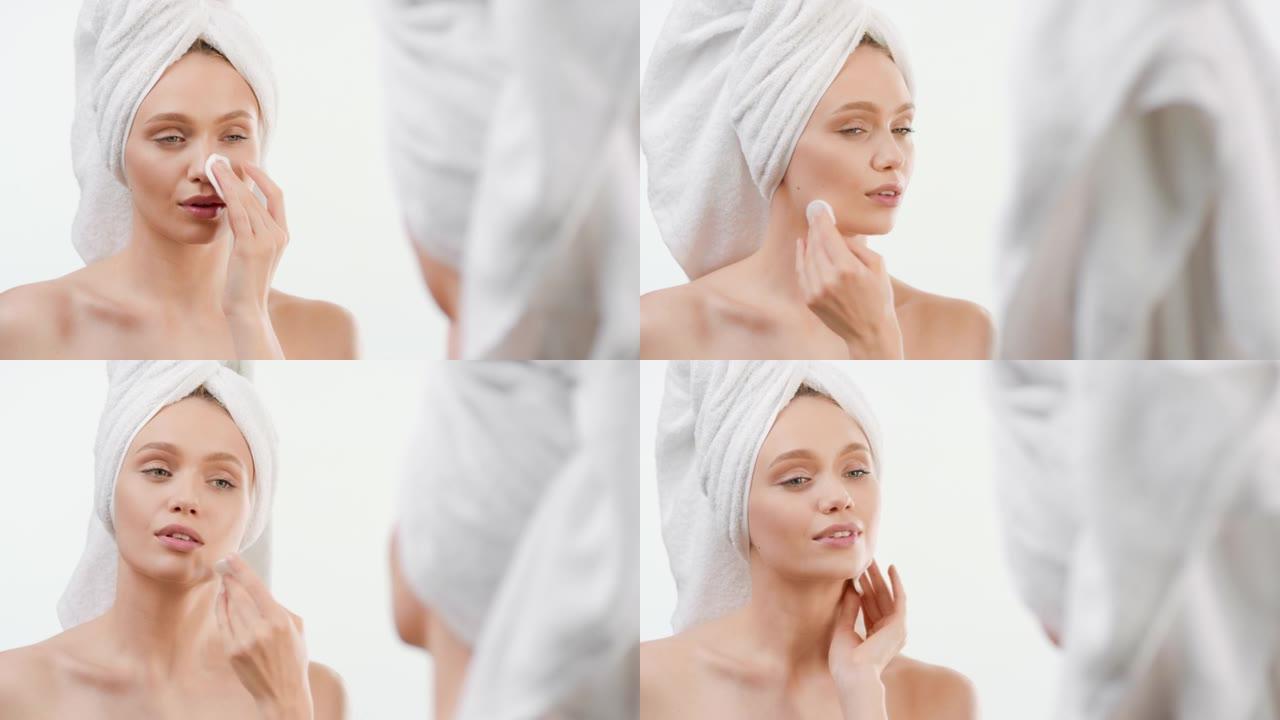 女人用化妆棉摸脸在镜子前微笑