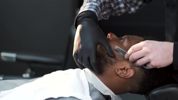 理发师用古典剃刀刮他的客户