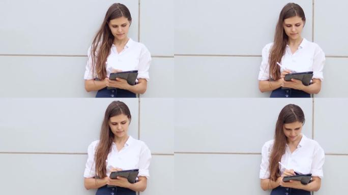 漂亮年轻的笑脸女商人在办公室外使用现代平板电脑。一位美丽的女性潮人的肖像为她的视频博客录制了一段视频
