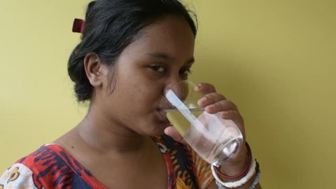 美丽的年轻印度女子喝着一杯新鲜的水，在家里竖起大拇指。饮用水概念的好处。