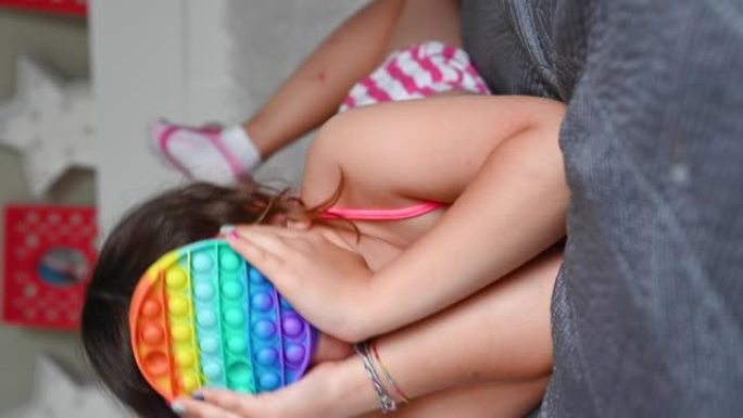 小女孩玩流行感官玩具。宝宝点击彩色彩虹柔软硅胶泡泡