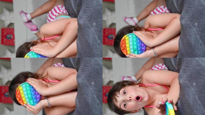 小女孩玩流行感官玩具。宝宝点击彩色彩虹柔软硅胶泡泡