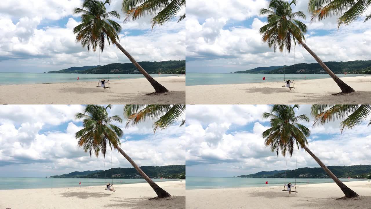 泰国普吉岛高清。热带海滩天堂，海滩秋千，白衬衫女孩。女人在美丽的热带海滩白色沙滩上的椰子棕榈树下摇摆