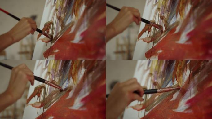 女人在室内手持画笔。不知名的画家在艺术工作室绘画。