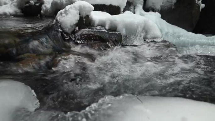 在针叶林中流淌的山区河流的死水特写。冰雪中的冰冻石头。横向移动滑动。广角