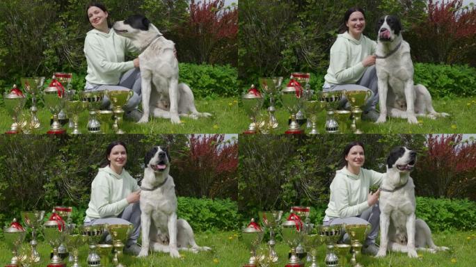 女宠物主人和她的获胜者中亚牧羊犬与狗一起颁奖，女子与阿拉巴伊在获胜杯附近