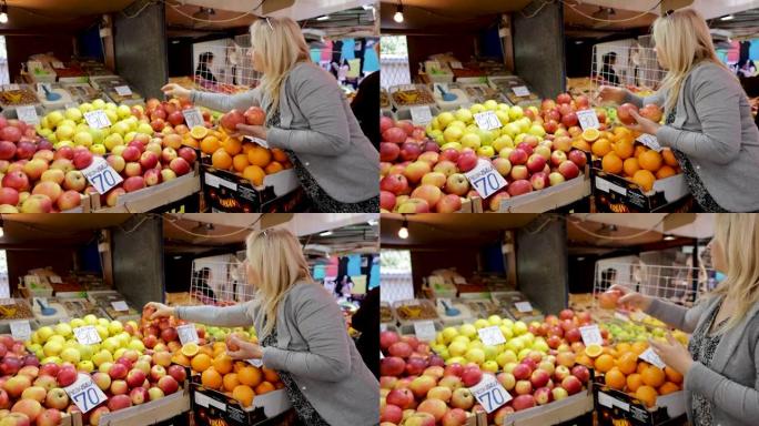 成熟的成年妇女在农贸市场安排红苹果