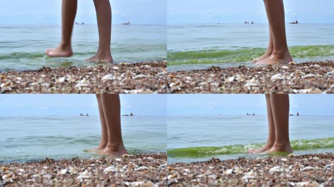 试图在海里洗澡的孩子。用脚在海里试水温的人。女孩在海里洗澡前用脚摸水。十几岁的腿出海了。