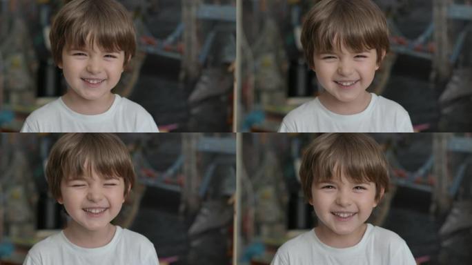 快乐的小孩大笑的特写肖像。小男孩在室内特写大笑。小男孩看着镜头微笑的肖像。面对有趣的沉思孩子。慢动作