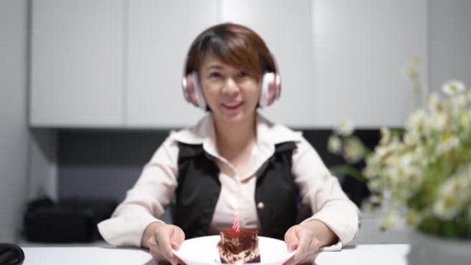 亚洲华裔妇女在家庭办公室工作，与她在其他分支机构的同事庆祝生日视频会议
