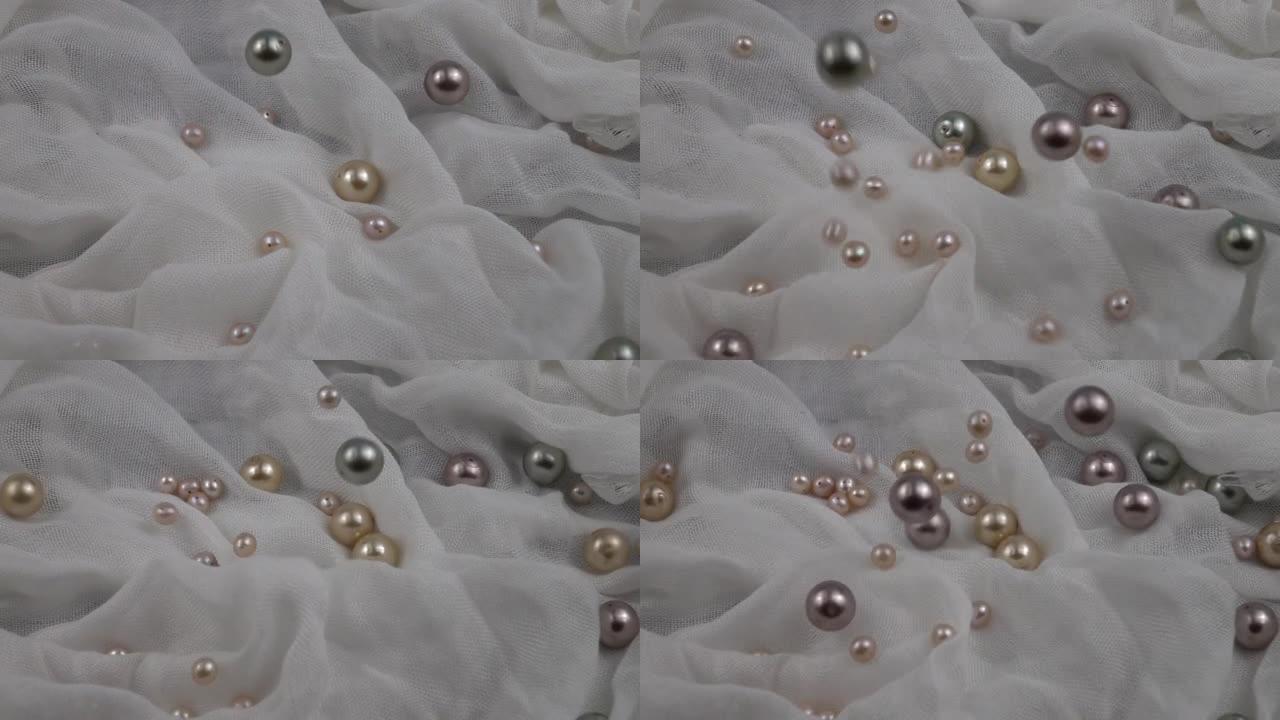 珍珠珠落在白色织物上，慢动作。