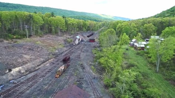废弃的窄轨煤铁路的鸟瞰图，生锈的料斗和货车以及支撑建筑物开始恢复