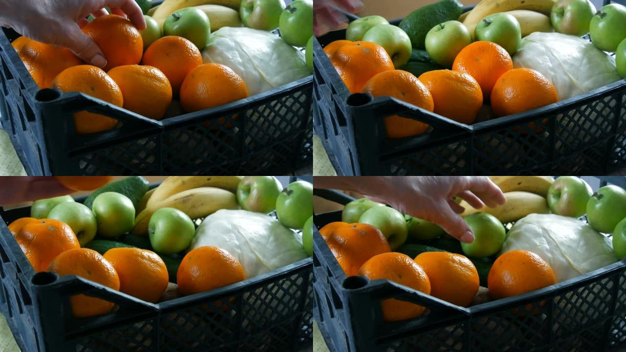 女性手拿普通话和苹果。装有水果和蔬菜的盒子特写。冠状病毒大流行和社会距离期间的食品配送服务。网上购物