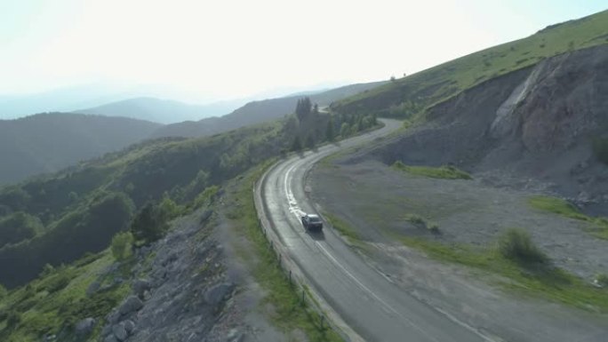 一辆黑色汽车在阳光明媚的山路上行驶